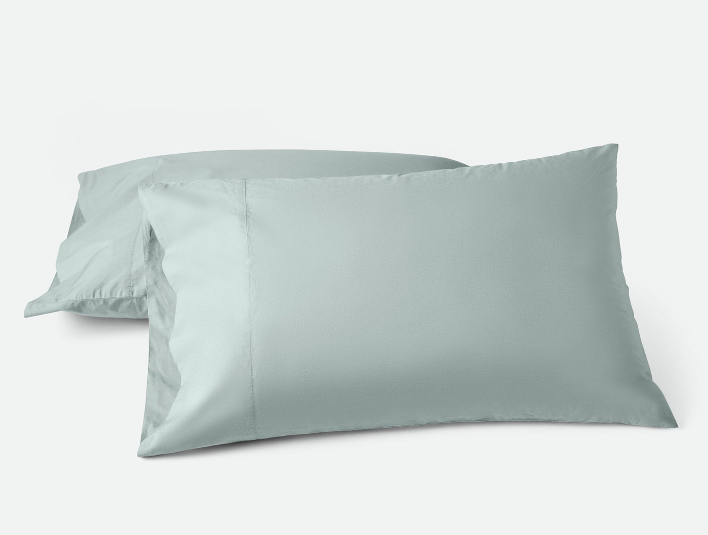 Pair of Coyuchi Refined Percale pillowcases in sage, shown stacked against white background.