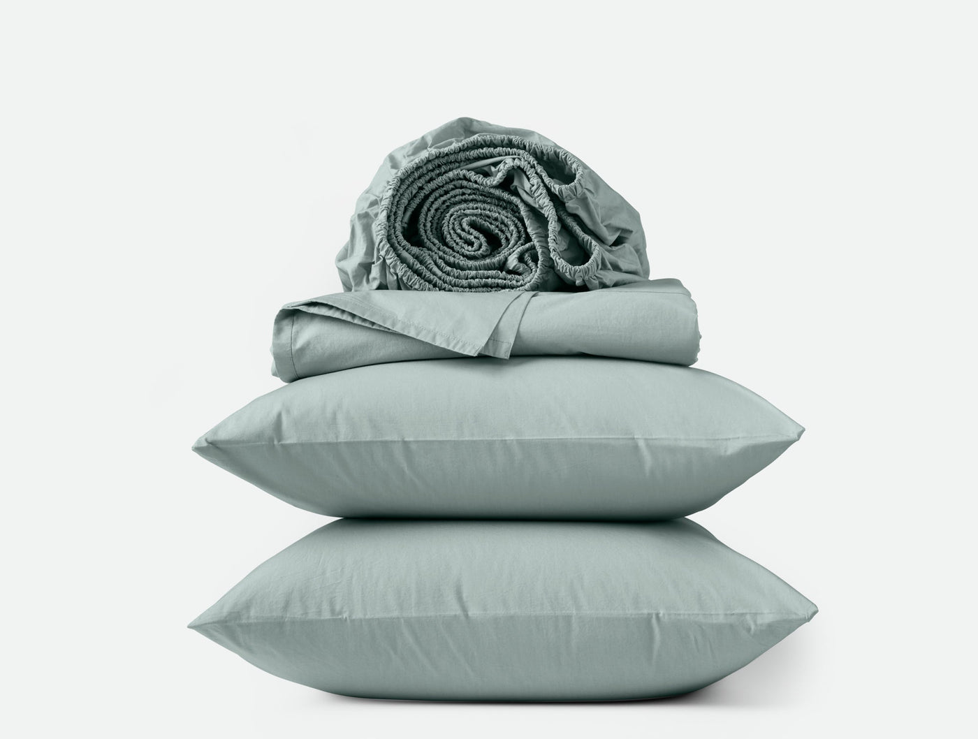 Sage green percale sheet set with two stacked pillowcases and rolled sheets on top.