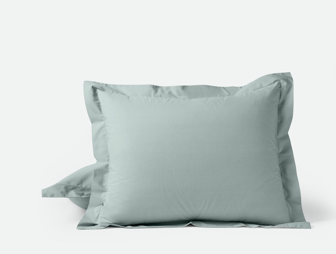Sage green percale pillow shams stacked, showing tailored flange edge detail.