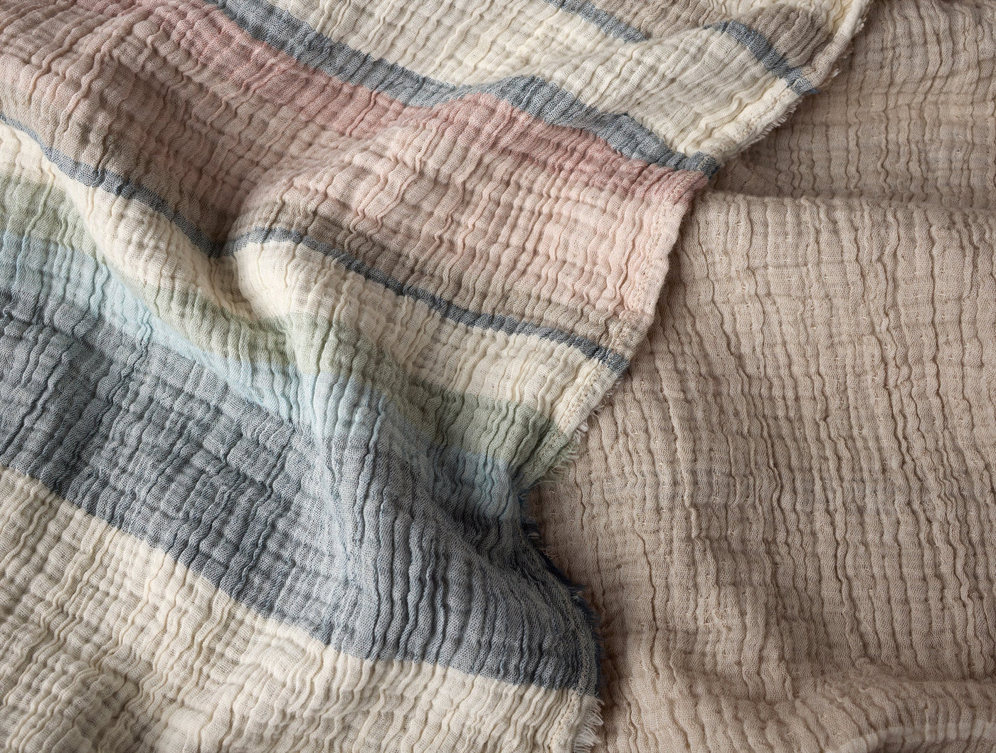 Close-up of crinkled matelasse weave with dusty rose, slate blue, and sand stripe detail.