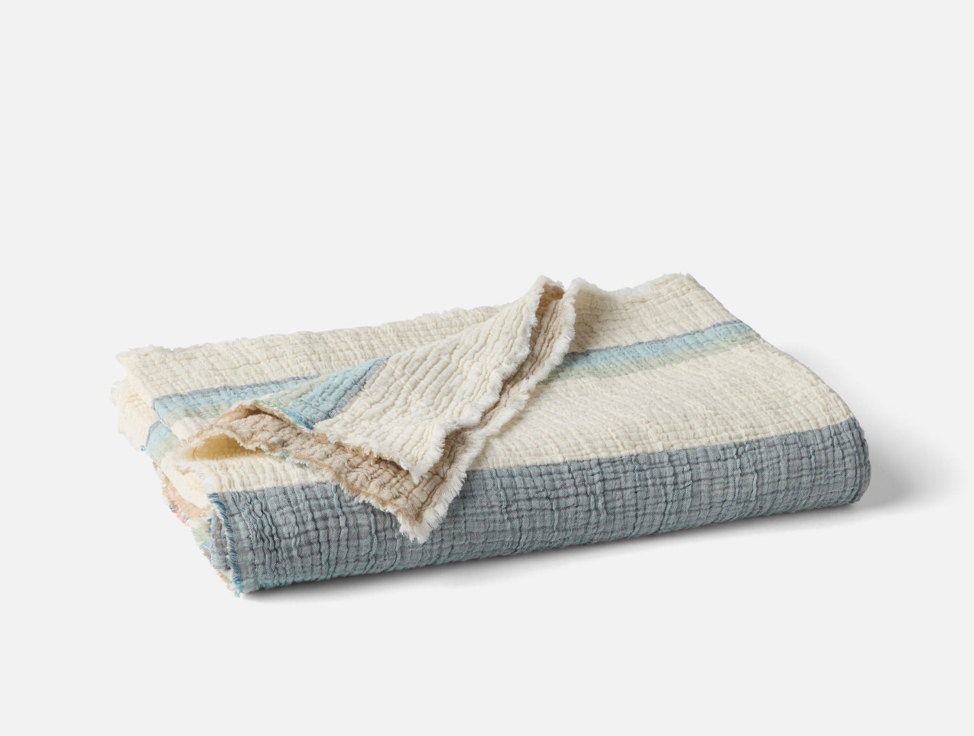 Coyuchi Topanga Matelasse throw folded, slate blue stripes with ivory fringe trim.