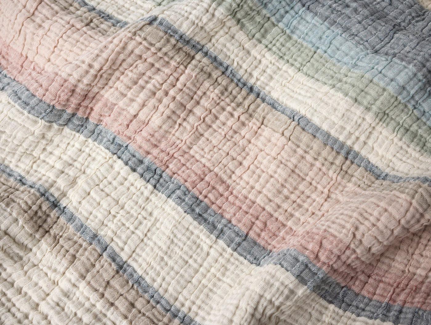 Close-up of crinkled matelasse weave with ivory, blush, sage, and slate blue stripes.