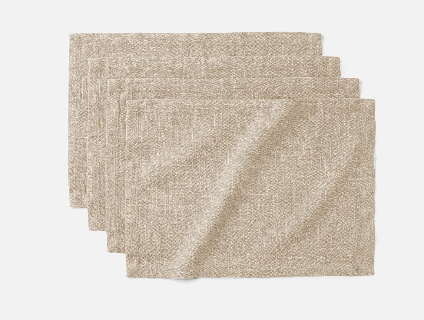 Four stacked Coyuchi Toro Canyon placemats in natural linen with visible woven texture.