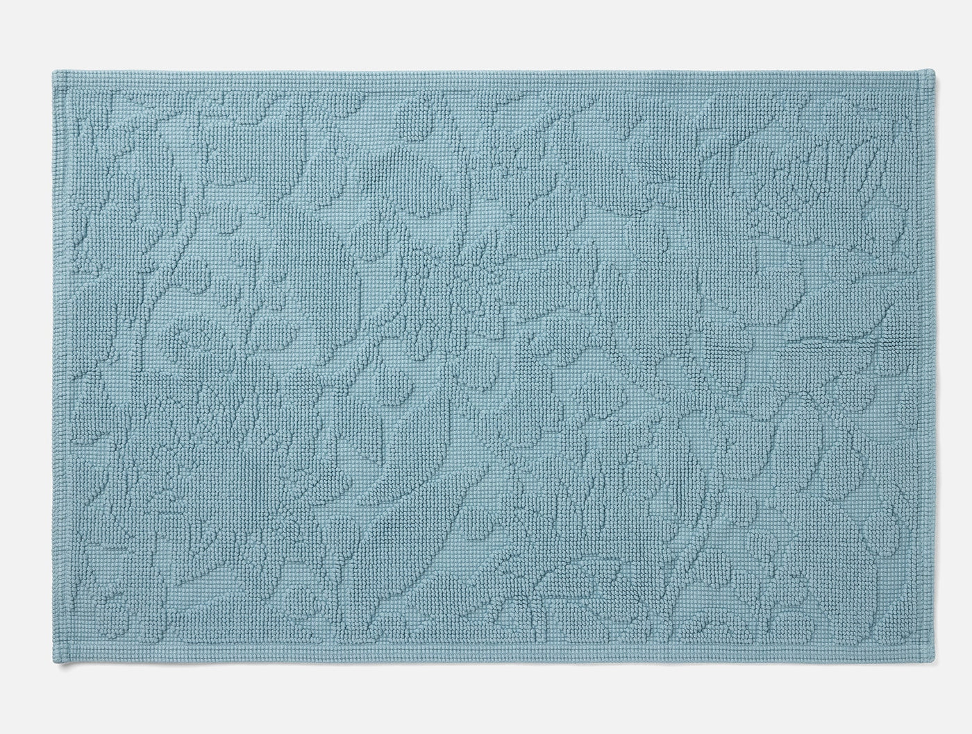Coyuchi Wildflower bath rug in slate blue with tonal floral jacquard texture, flat lay view.