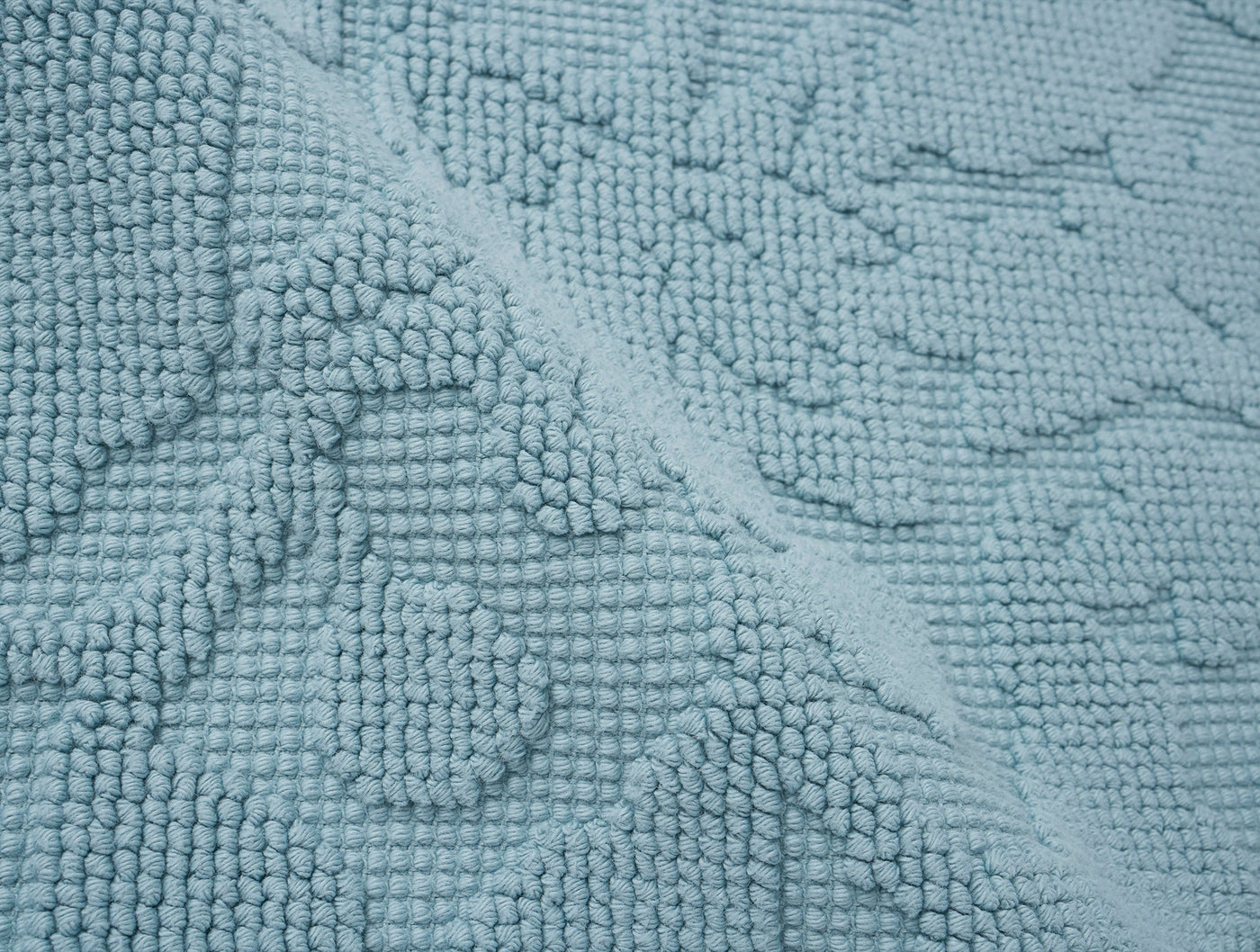 Close-up of Coyuchi Wildflower bath rug in sky blue, showing raised floral loop-pile texture.