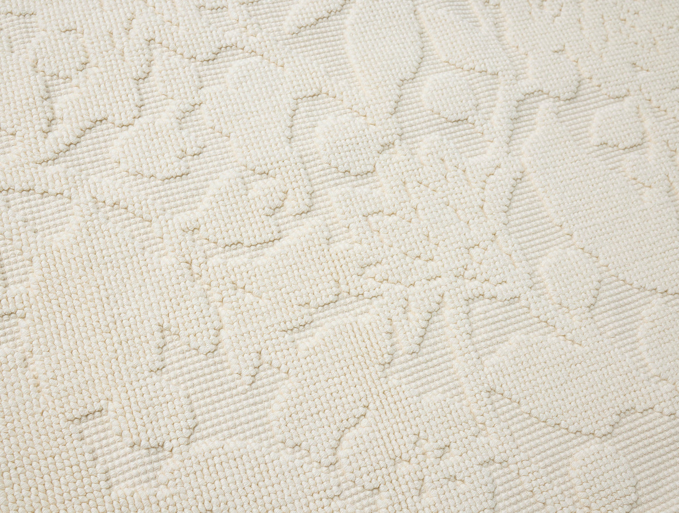Close-up of ivory cotton Coyuchi Wildflower table runner showing embossed floral texture.