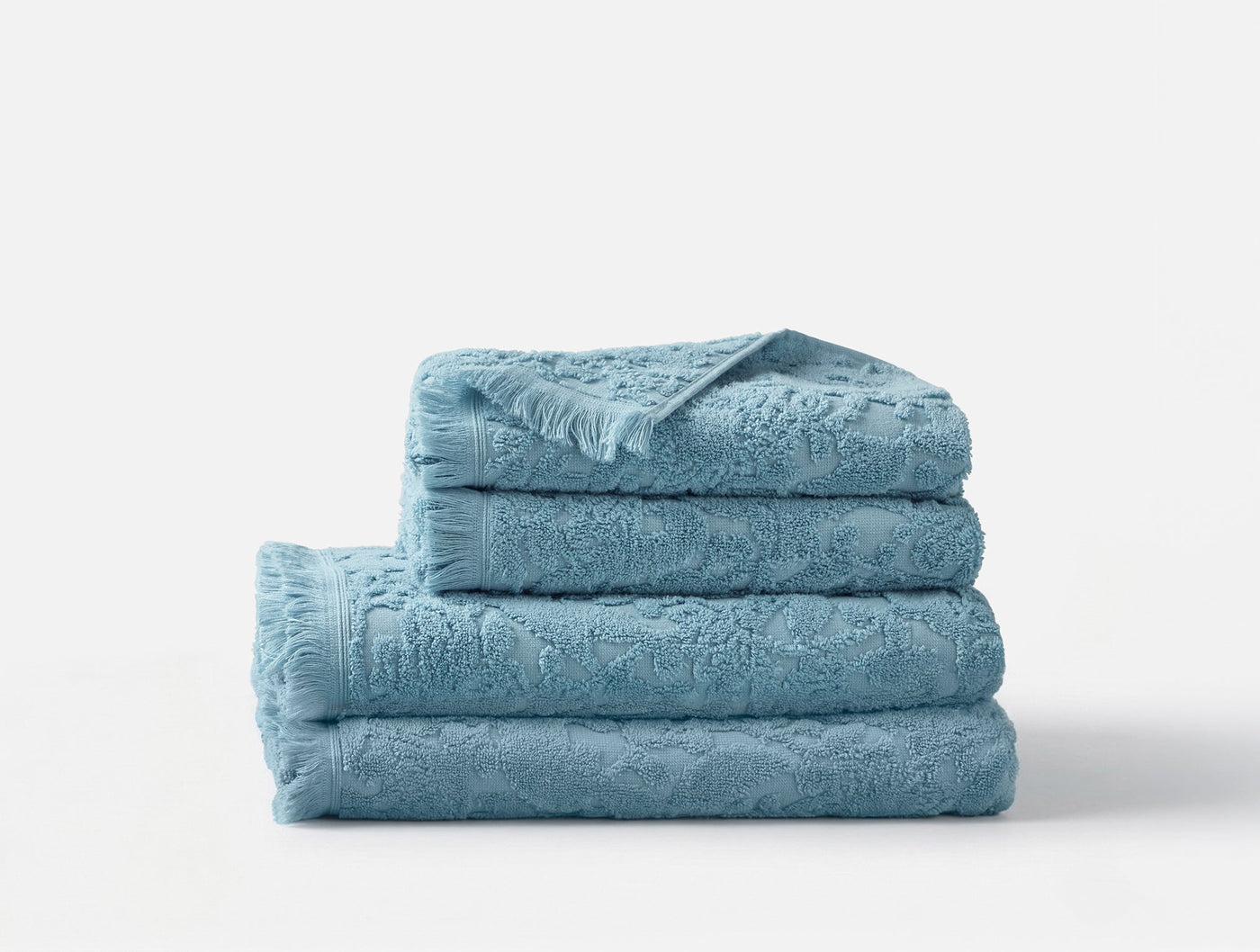 Close-up of stacked Coyuchi Wildflower towels in sky blue with floral jacquard texture.