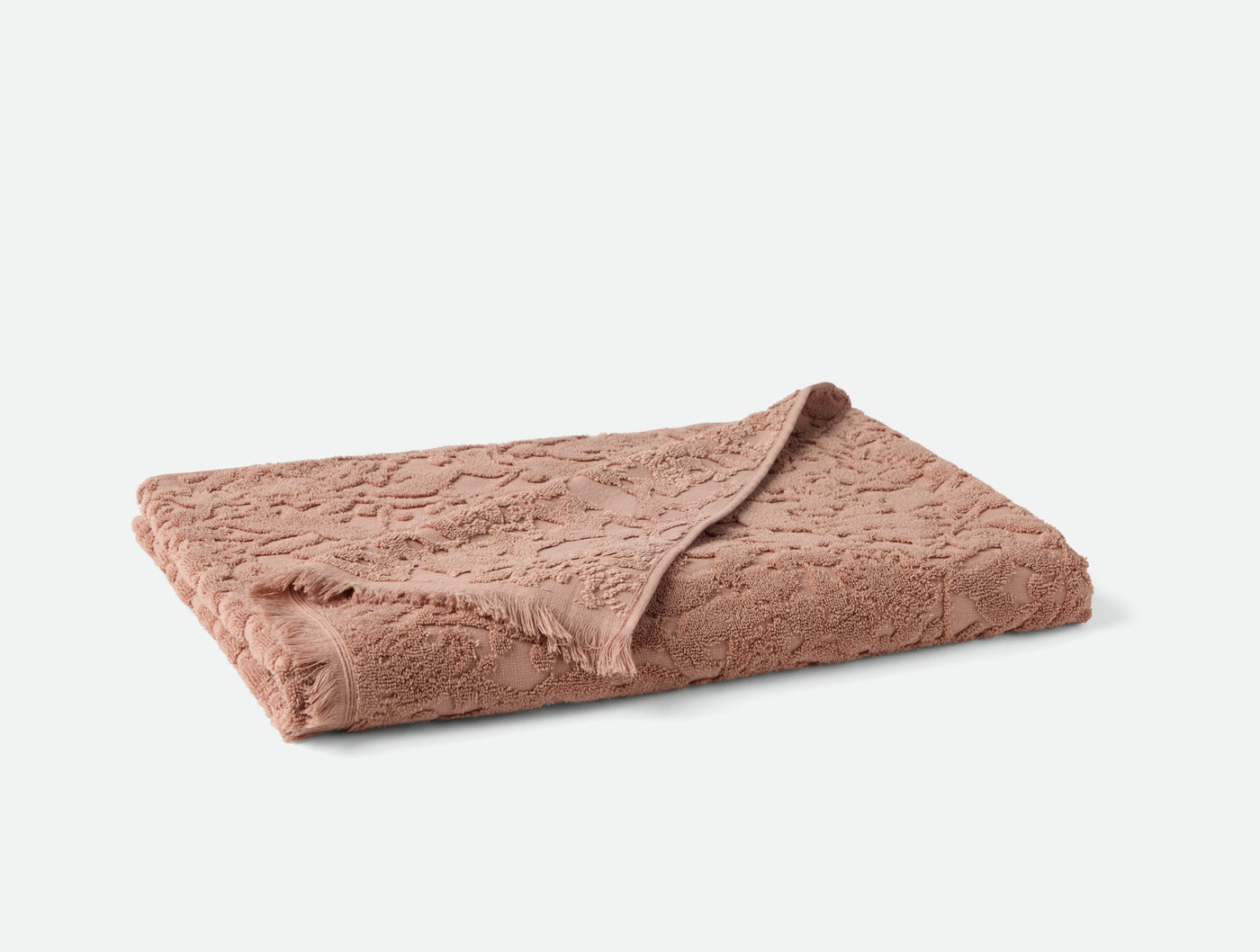 Folded dusty rose hand towel showing tonal floral jacquard texture on terry surface.