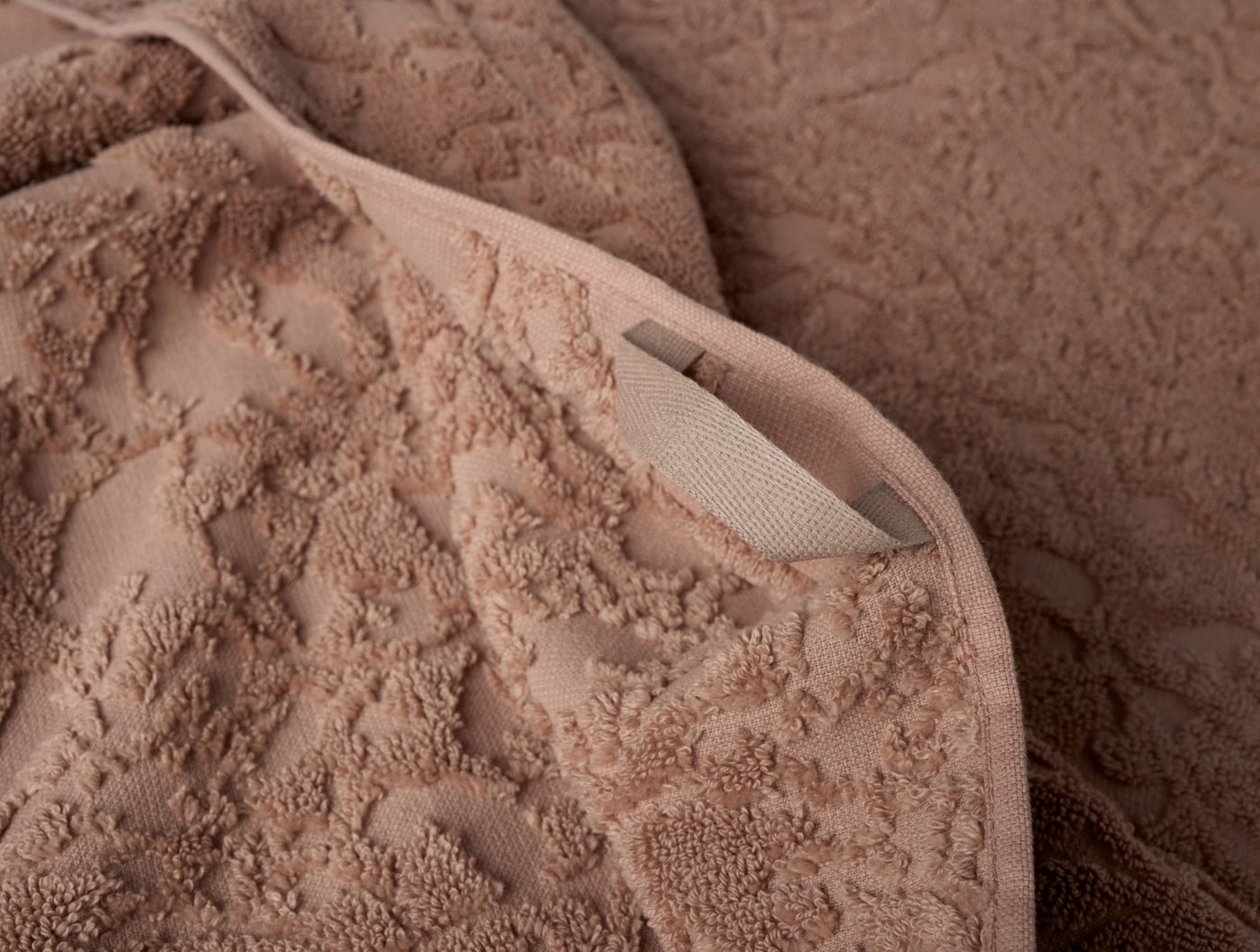 Close-up of Coyuchi Wildflower hand towel label and sculptural floral terry texture in clay.