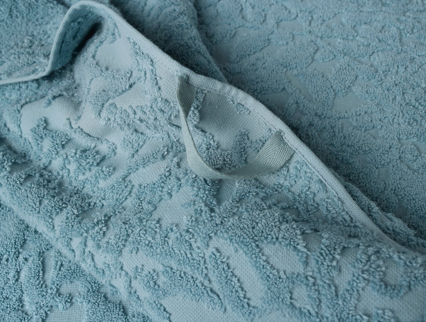 Close-up of Coyuchi Wildflower bath towel hem and folded edge in sky blue jacquard terry.