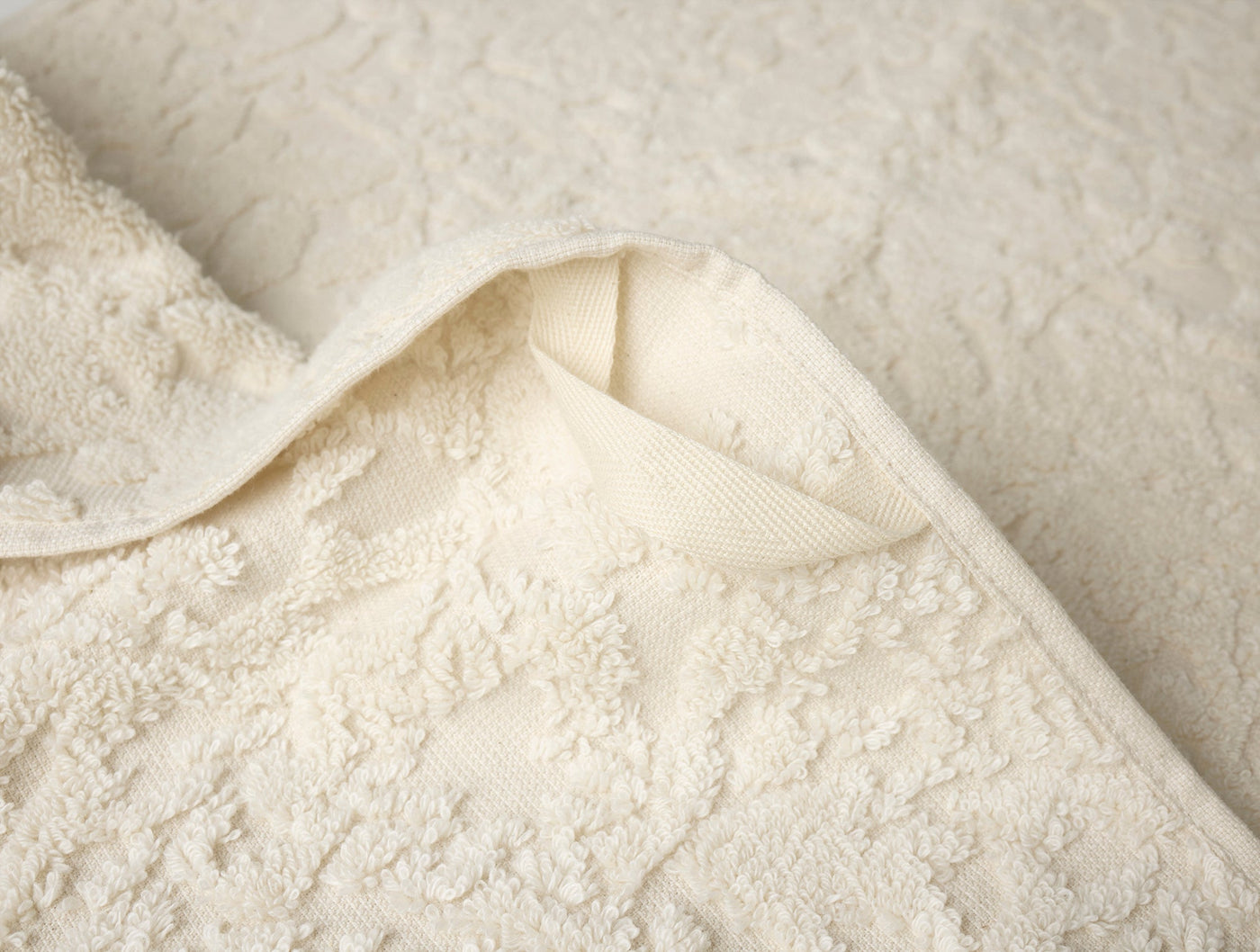 Corner fold detail revealing ivory terry weave and ribbed hem of Coyuchi Wildflower hand towel.