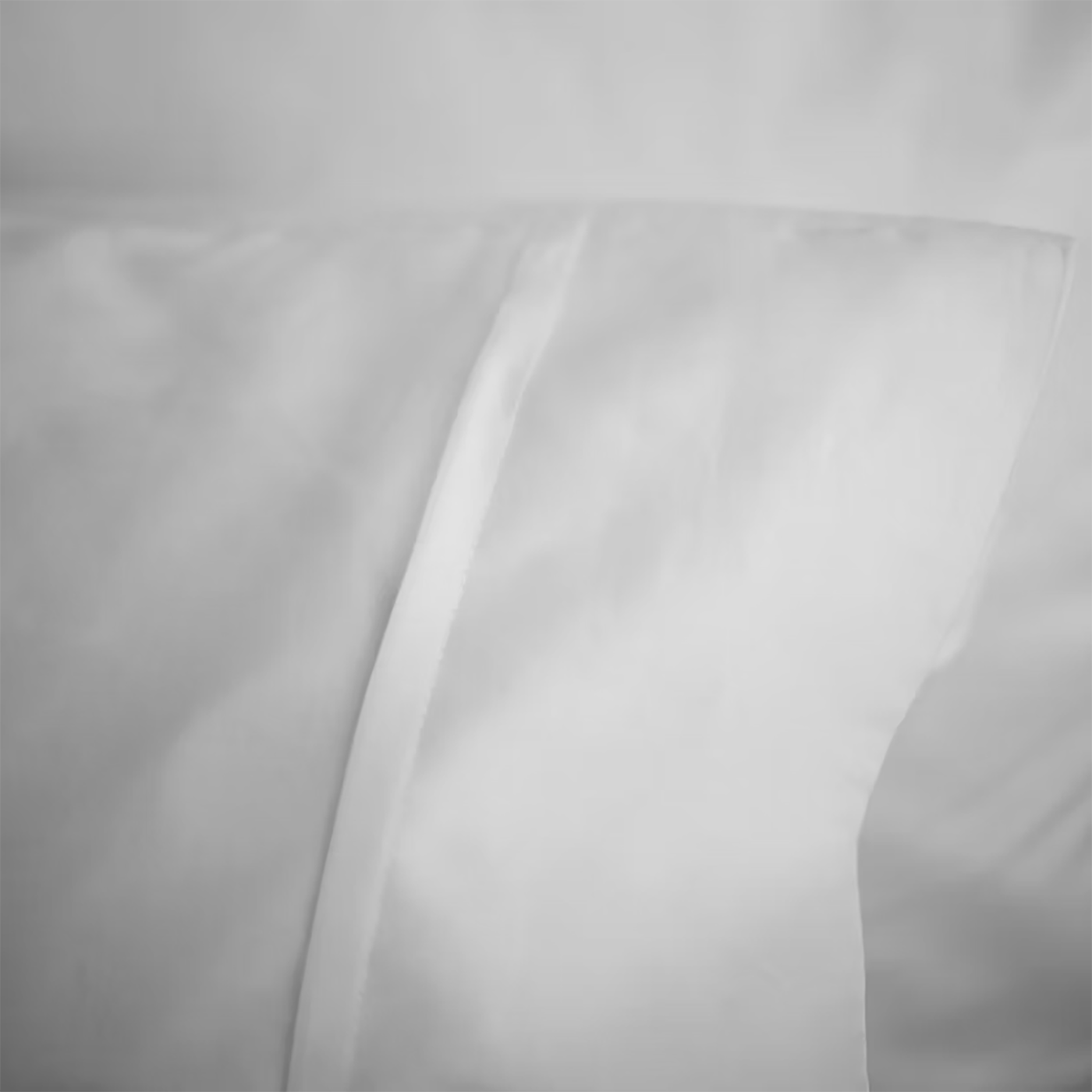 Close-up of white sateen fitted sheet corner showing smooth lustrous fabric drape.