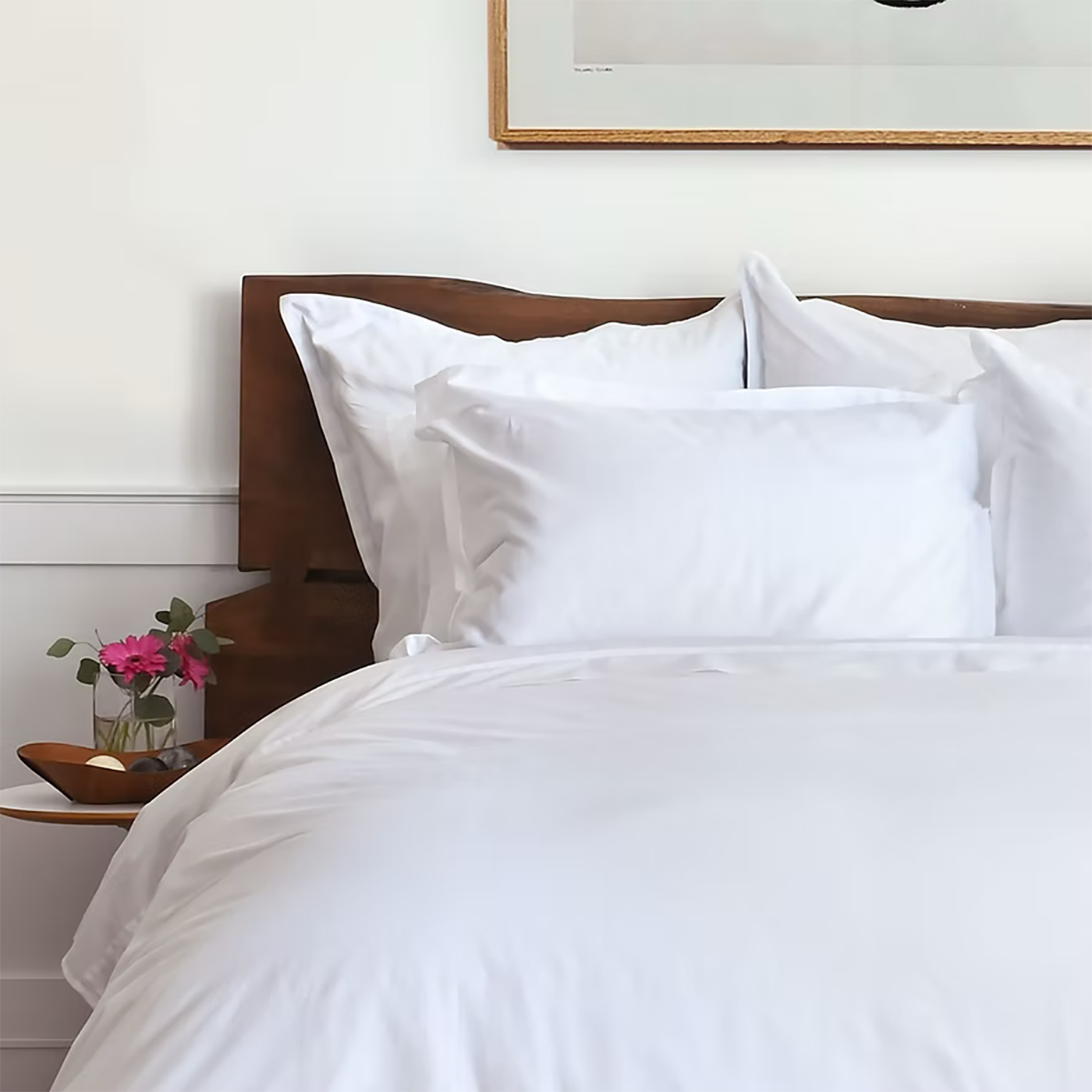 St. Geneve Capri Sateen fitted sheet in white, styled on a bed with wood headboard.