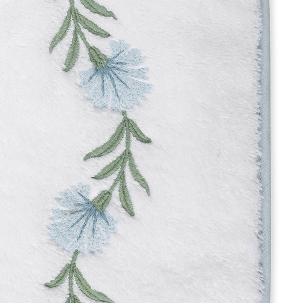 Close-up of ice-blue floral and sage green stem embroidery on white terry cloth edge.