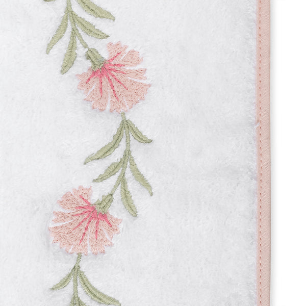 Close-up of blush floral embroidery with sage green stems on white terry cloth border.