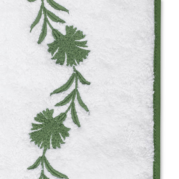 Close-up of green embroidered floral vine border on white terry cloth bath sheet.