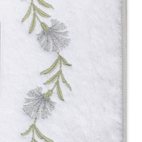 Close-up of silver floral and sage green leaf embroidery border on white terry bath sheet.