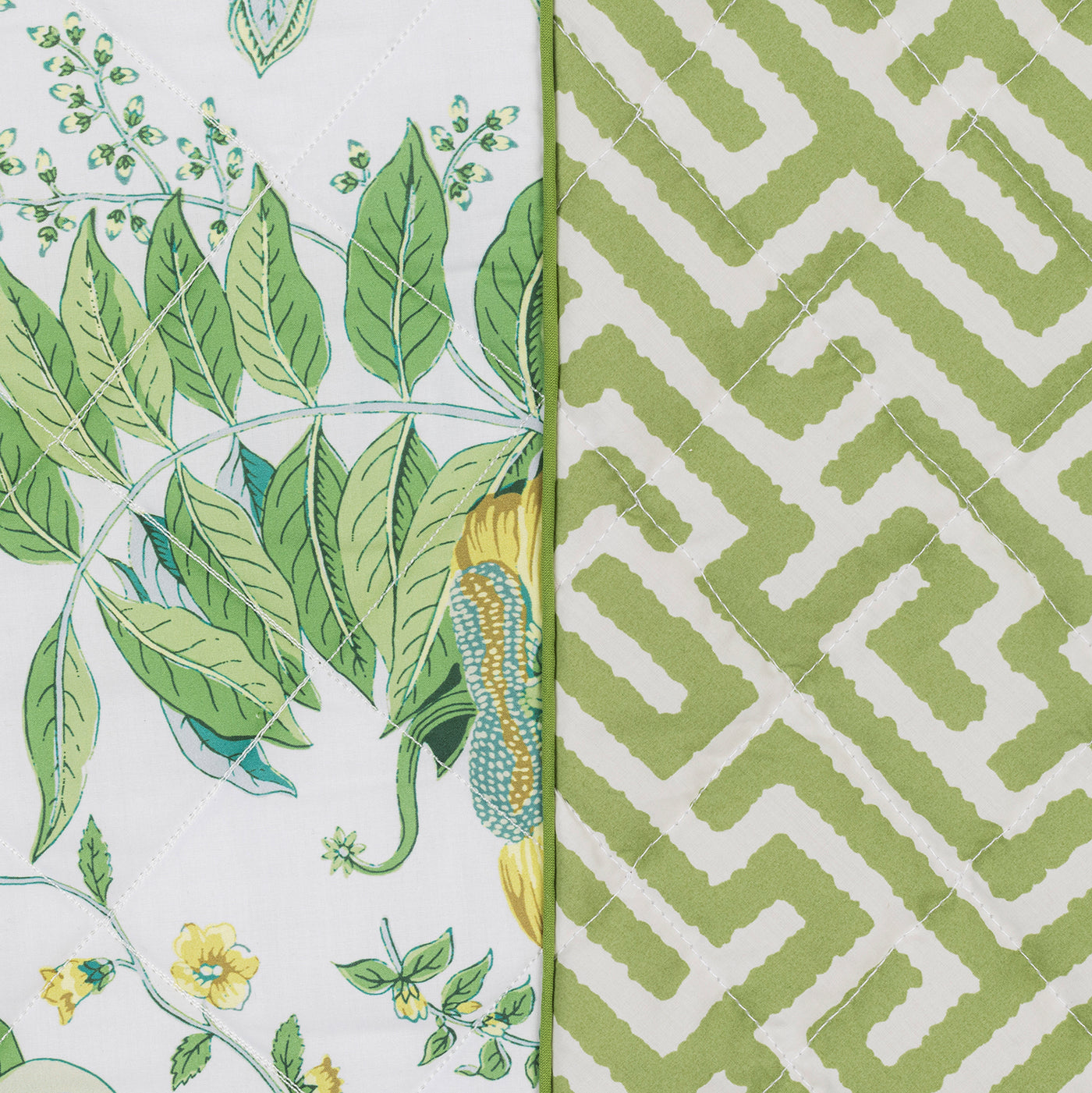 Close-up of Matouk's Reversible Quilted Lumbar Pillow Cover featuring green botanical and geometric maze prints, joined with white stitching—ideal for adding customizable decorative flair to your space.