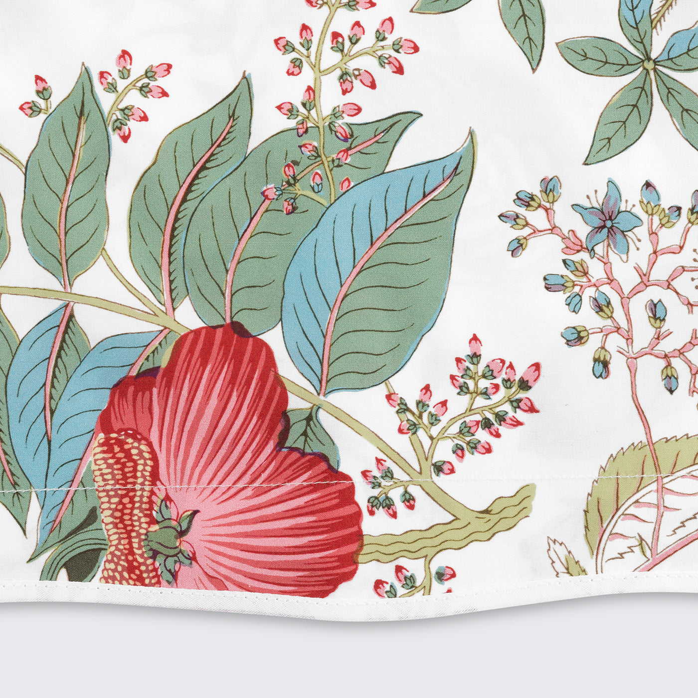 Close-up of Matouk Pomegranate botanical print with crimson blooms and sage leaves on white.