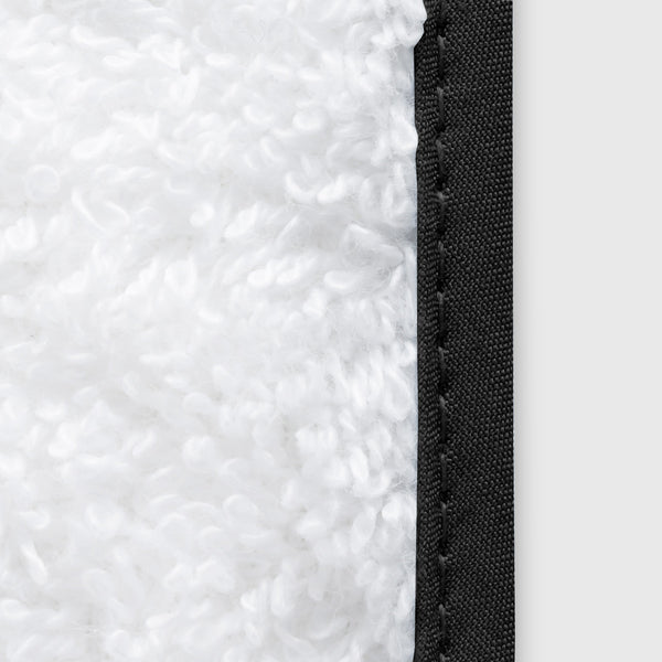 Close-up of white terry fabric with contrast black piped edge stitching.