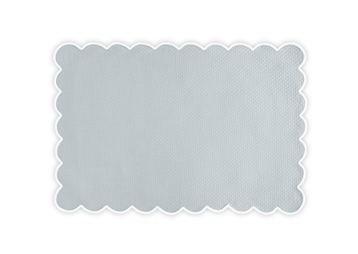 The Matouk Savannah Gardens Placemat Set features rectangular light gray placemats with a textured diamond pique surface and scalloped edges, showcased against a white background.