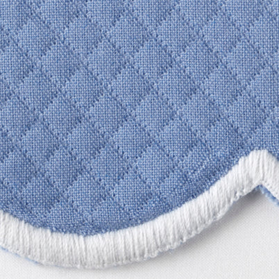 Close-up of periwinkle quilted cotton placemat with scalloped white trim edge.