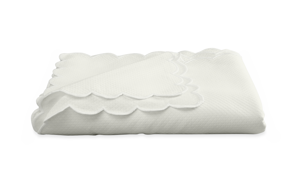 A folded white Savannah Gardens Tablecloth by Matouk, featuring diamond pique and scalloped edges, is displayed on a plain white background.