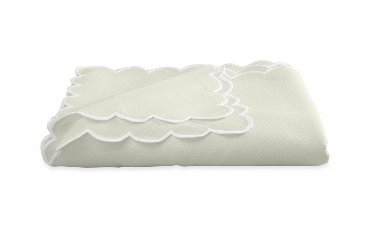 The Matouk Savannah Gardens Tablecloth features a cream diamond pique pattern, scalloped edges, and white trim—an elegant, easy-care addition to your table linens. Displayed on a plain white background.
