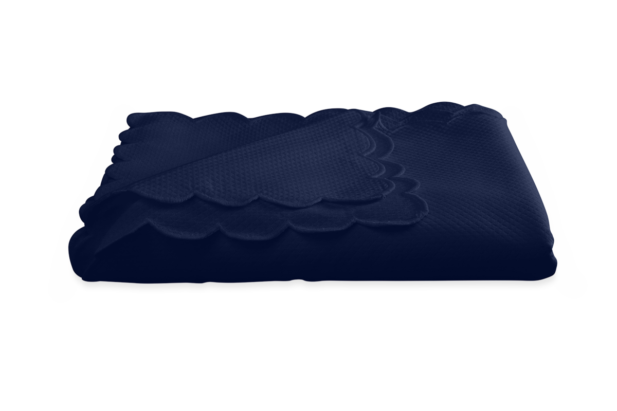 The Savannah Gardens Tablecloth by Matouk, in dark blue diamond pique with scalloped edges, is neatly folded on a white background, offering an easy-care option to complement your table linens.