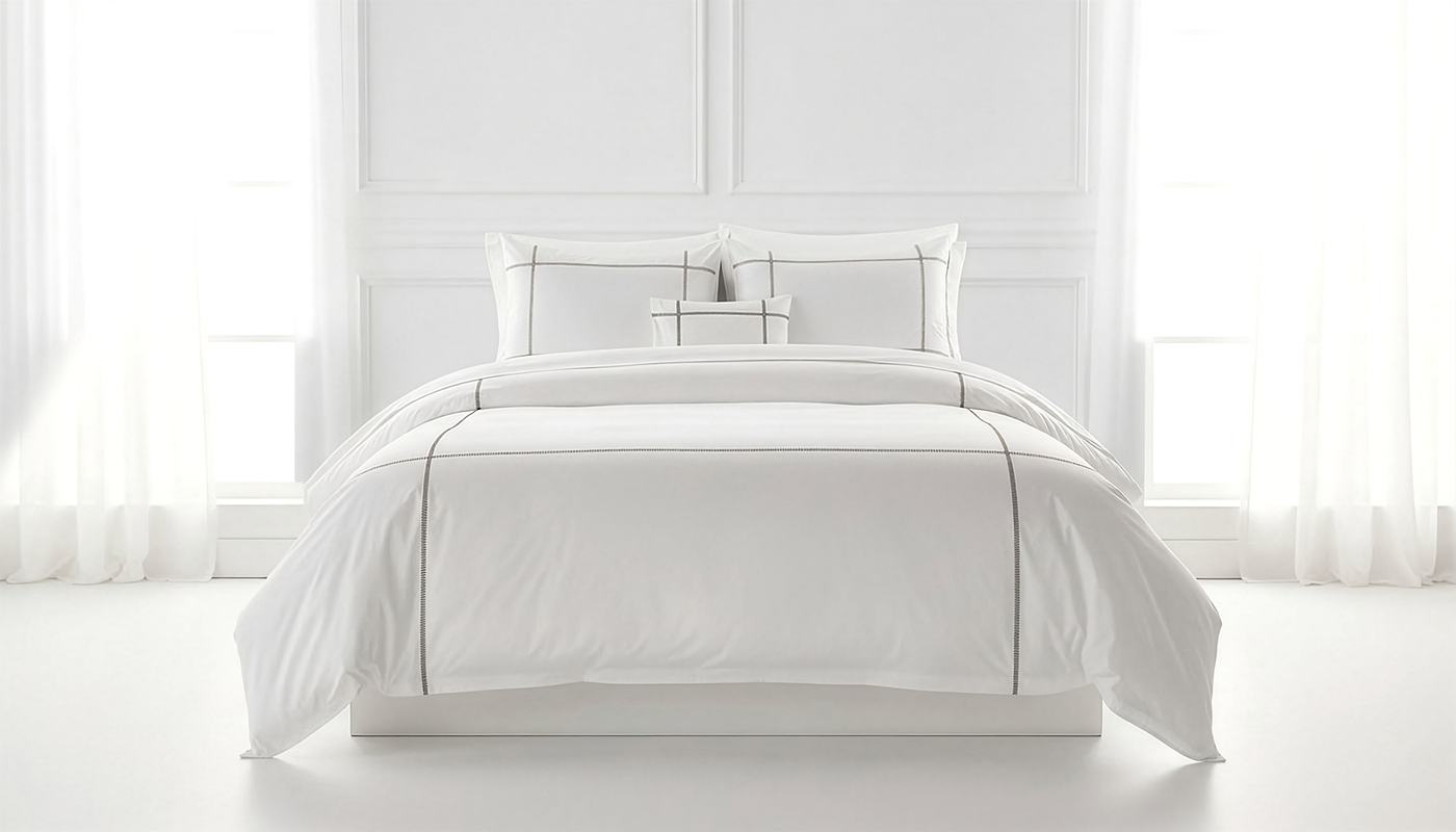 Henry Handwork Scala white cotton bedding set with charcoal border detail on made bed.