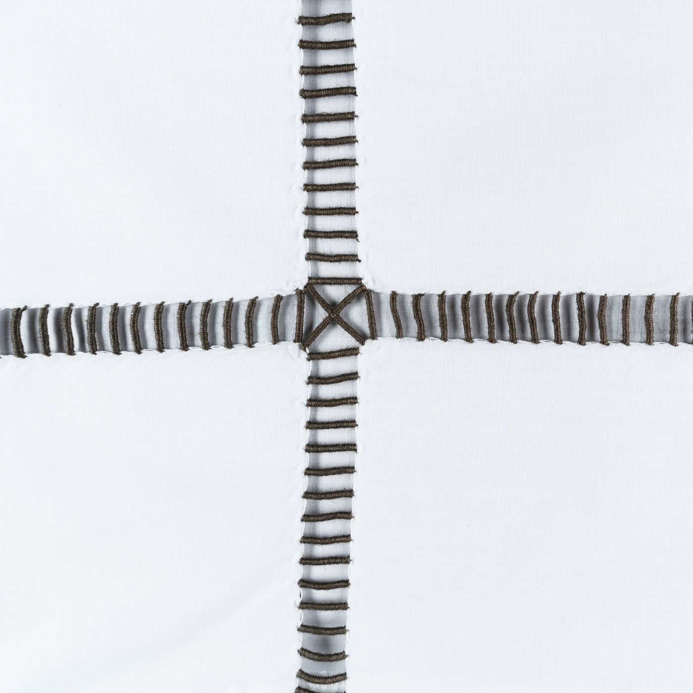 Close-up of Scala charcoal ladder-stitch embroidery cross detail on white linen.