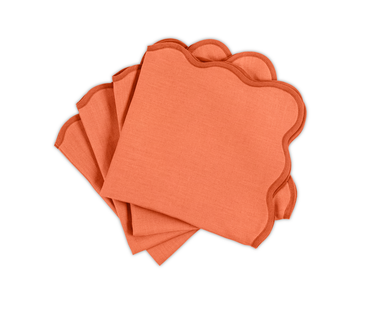 The Matouk Scallop Edge | Napkin Set includes four orange napkins with elegant scalloped edges, neatly stacked on a white background—perfect for adding a unique touch to your tablescape.