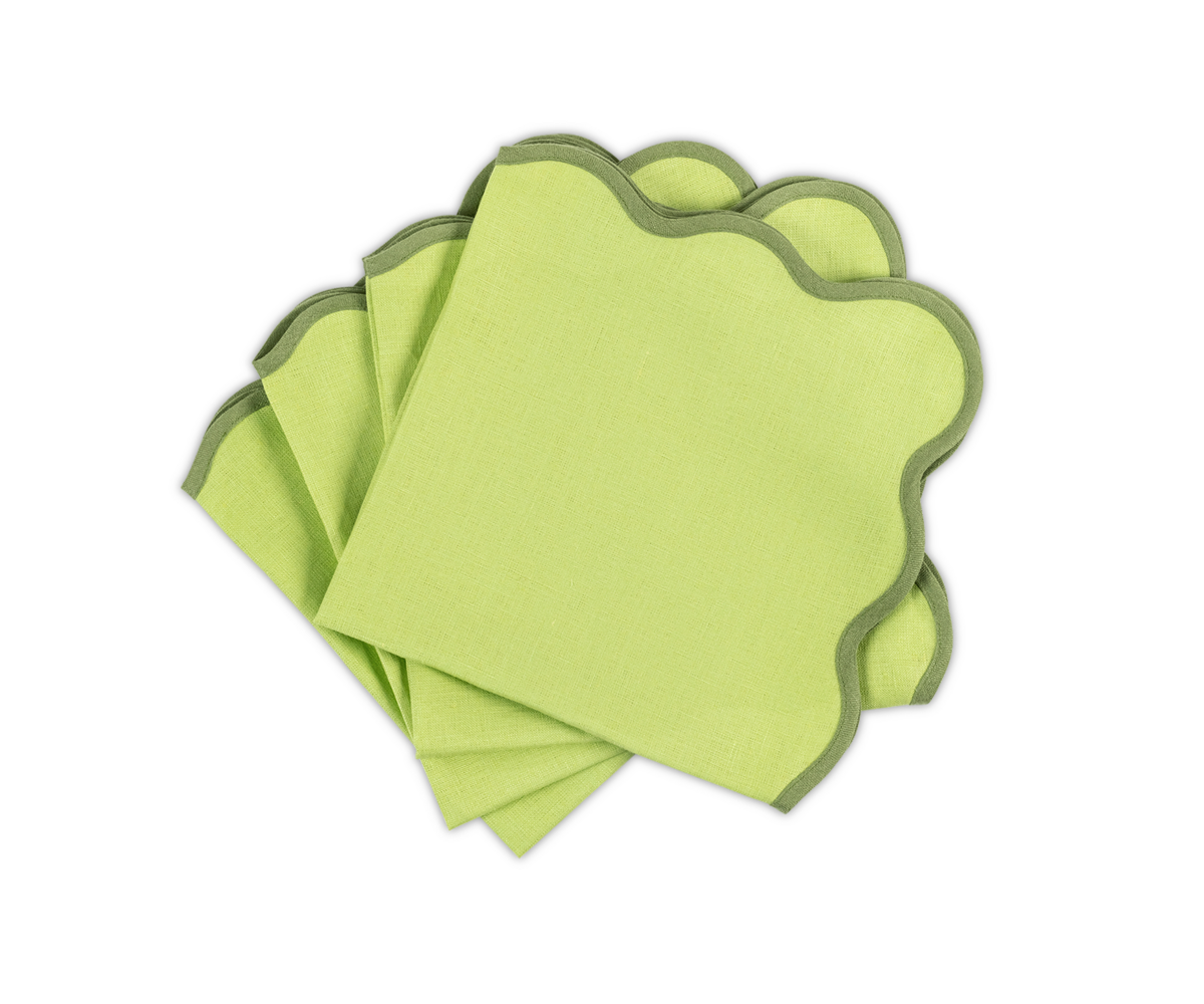 The Matouk Scallop Edge | Napkin Set, featuring four light green napkins with wavy dark green borders, is beautifully fan-arranged on a white background—ideal for a unique tablescape with linen placemats.