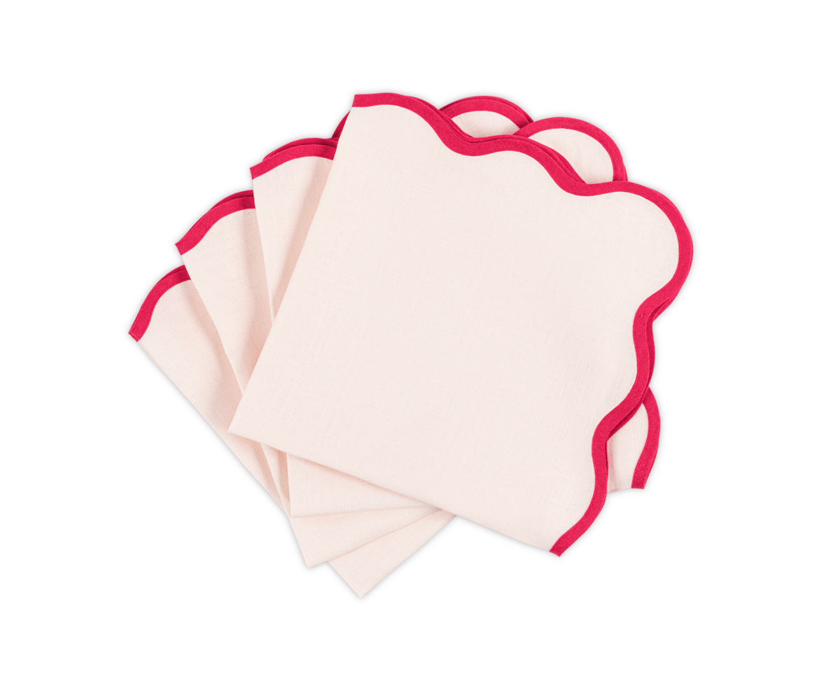 The Matouk Scallop Edge Napkin Set features four folded cream napkins with red scalloped edges, beautifully stacked on a white background—ideal for elevating your tablescape or pairing with linen placemats.