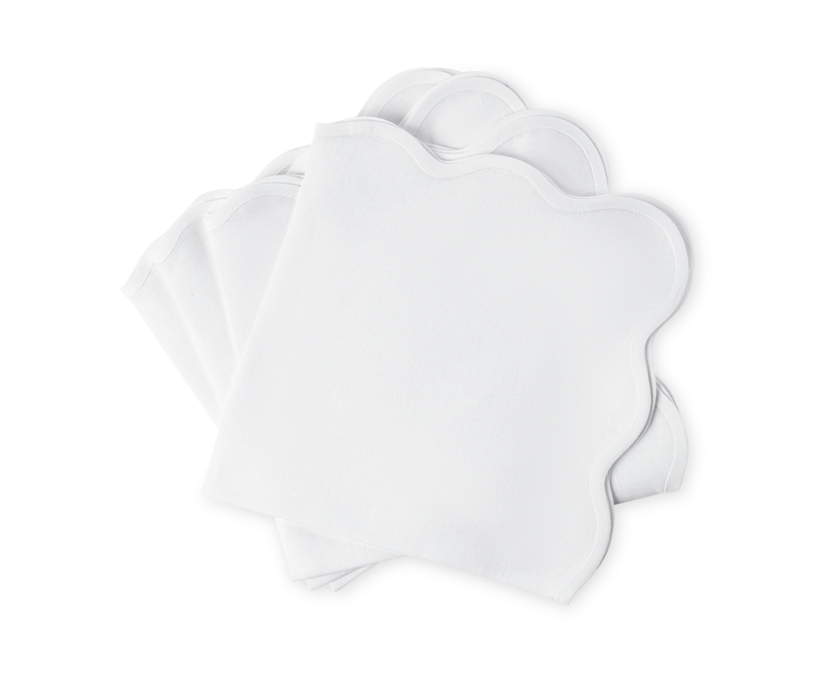 The Matouk Scallop Edge Napkin Set includes four white napkins with scalloped edges, ideal for elevating any tablescape or pairing with your favorite linen placemats.