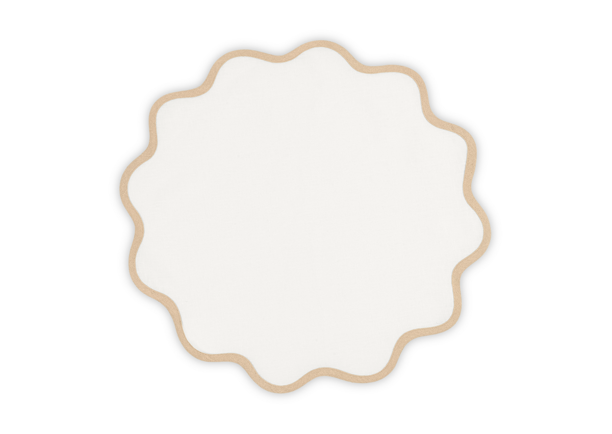 The Matouk Scallop Edge Placemat Set features round, white linen placemats with tan, scalloped edges, bringing charm to any tablescape against a simple white background.