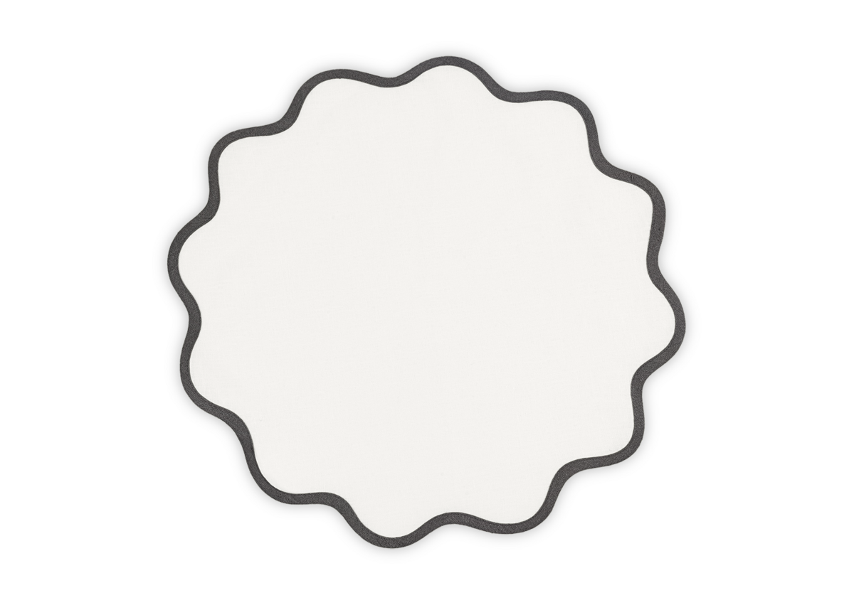 The Scallop Edge | Placemat Set by Matouk features round white linen placemats with black-outlined wavy scalloped edges, perfect for a unique tablescape. Shown on a white background.