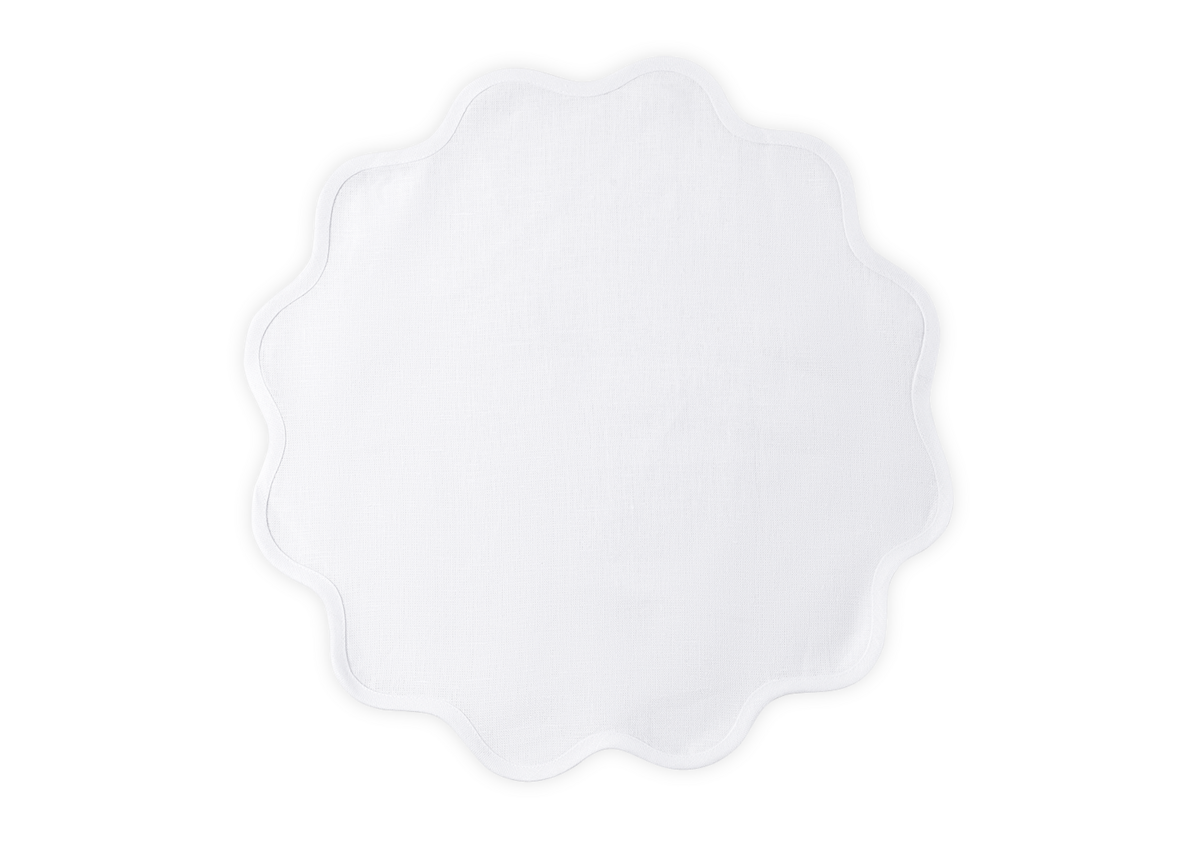 The Scallop Edge Placemat Set by Matouk features white, round linen placemats with scalloped edges—ideal for enhancing any tablescape with a touch of elegance.