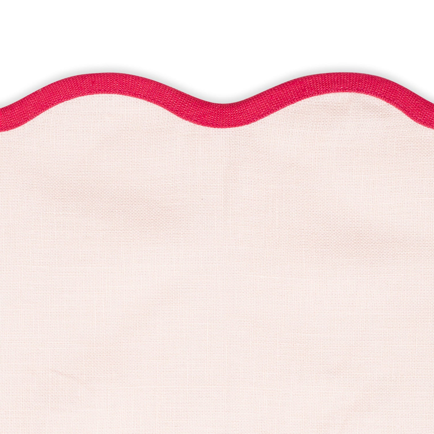 A close-up of Matouk’s Scallop Edge | Napkin Set shows light pink napkins with a bright red trim, perfect for adding charm to your unique tablescape.