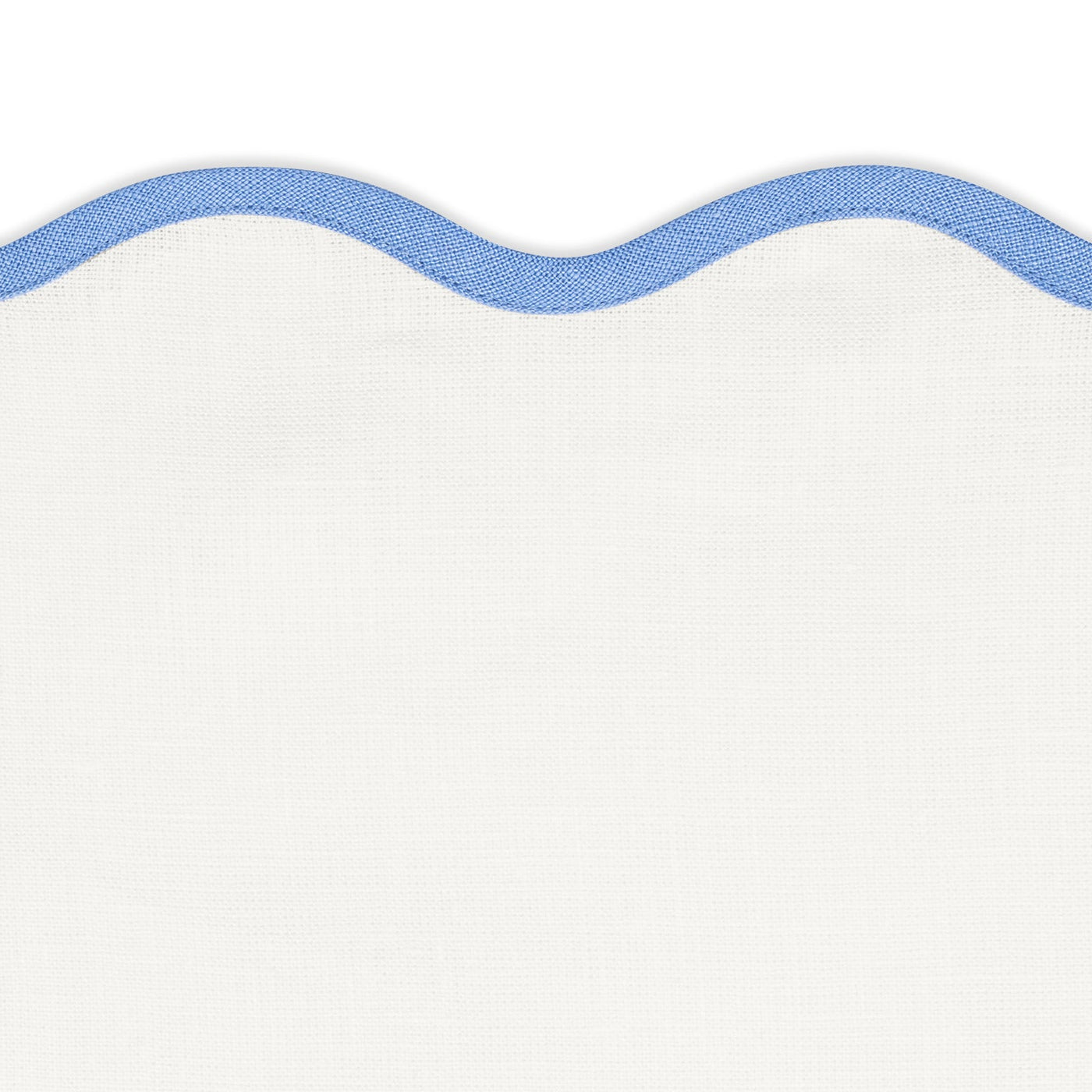 White fabric with a wavy blue border along the top, set against a white background—perfect for a unique tablescape or pairing with Matouk’s Scallop Edge | Napkin Set and linen placemats.