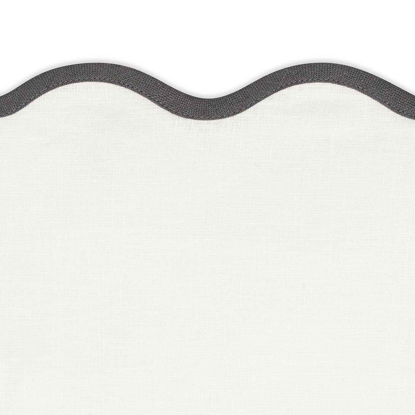 White textured fabric with a dark, wavy border along the right edge—ideal for a distinctive tablescape or pairing with the Matouk Scallop Edge | Napkin Set.