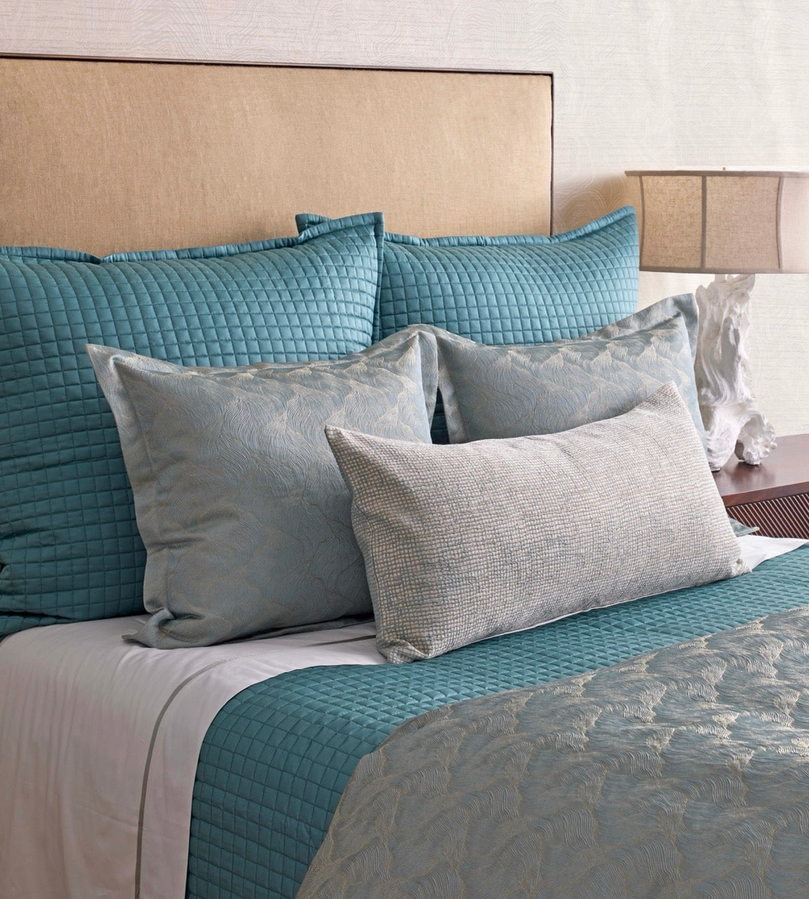 Close-up of Ann Gish Screen pillow in silver-grey textured fabric on styled teal bedding.