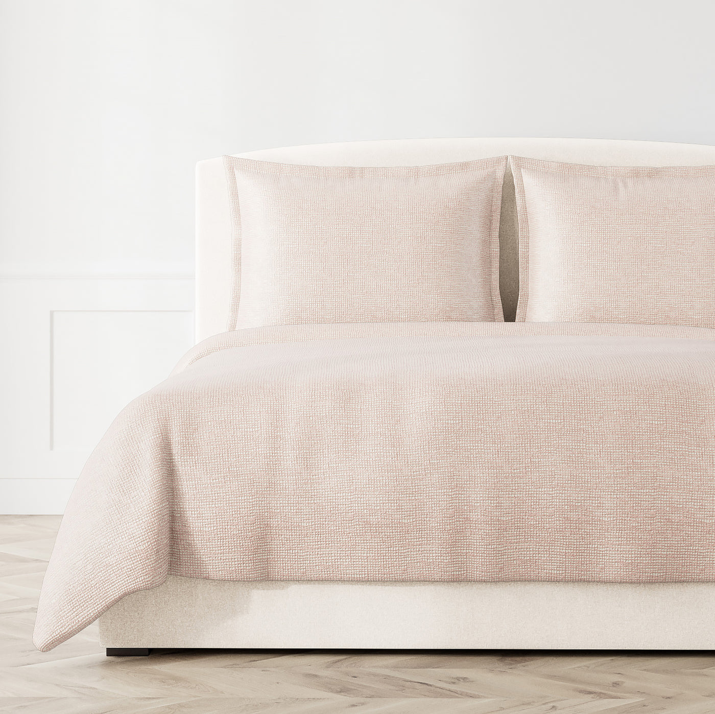 Blush woven coverlet and shams styled on a bed, showing subtle textured screen pattern.
