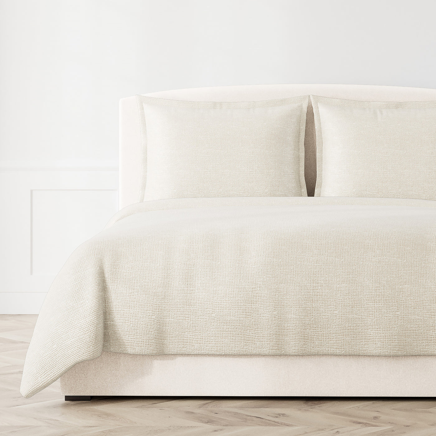 Ivory woven coverlet and shams styled on a bed, showing textured screen pattern detail.