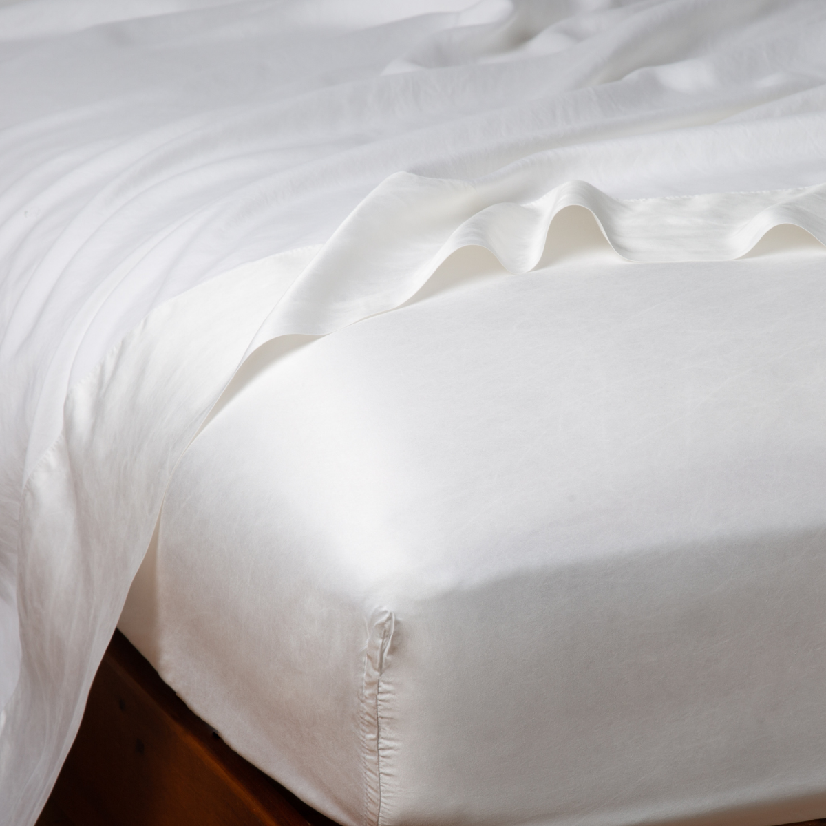 Bella Notte Seraphina fitted sheet in White, shown on bed with lustrous silky drape.