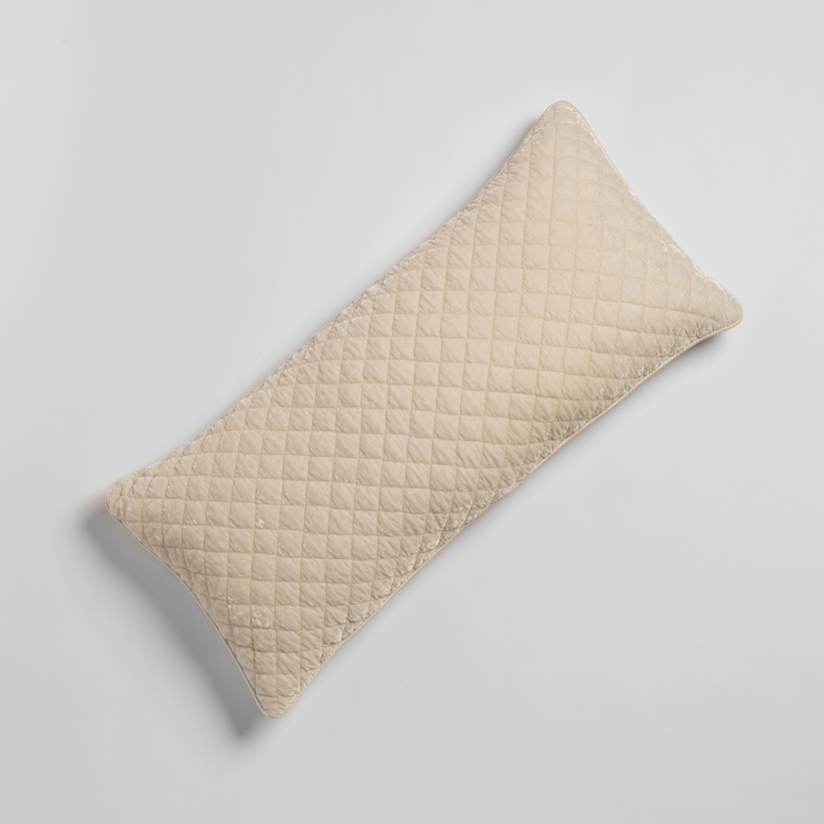 Flat overhead view of Bella Notte Silk Velvet quilted throw pillow in Crema diamond pattern.
