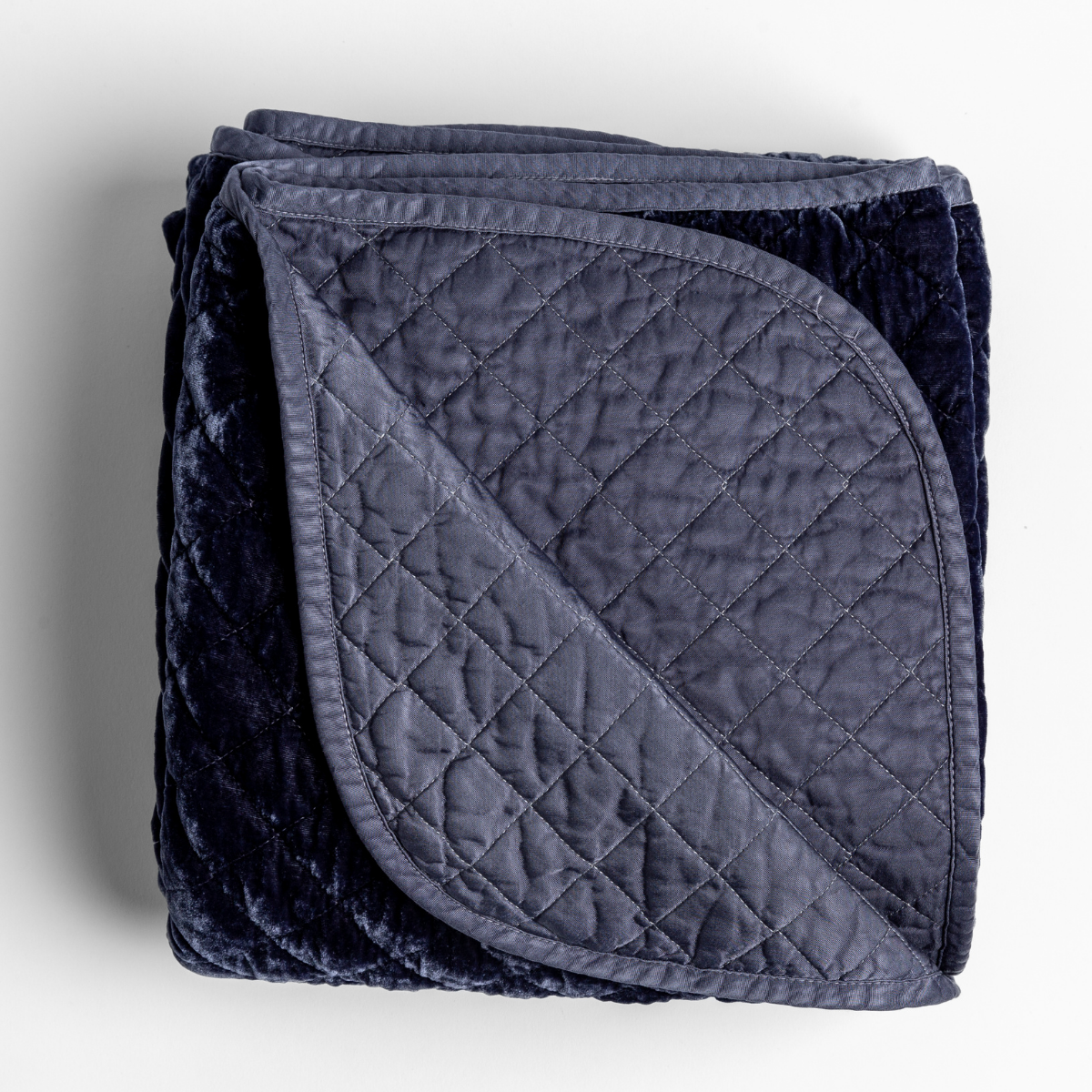 Corner fold detail of Bella Notte Silk Velvet Quilted Blanket in French Lavender, showing diamond-quilted reverse.