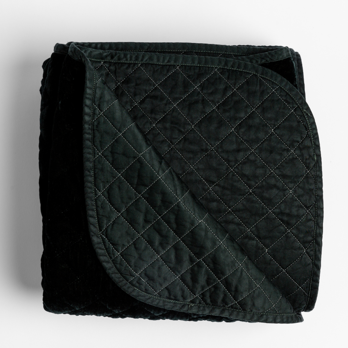 Bella Notte Silk Velvet quilted blanket in Juniper, folded to show diamond stitching detail.