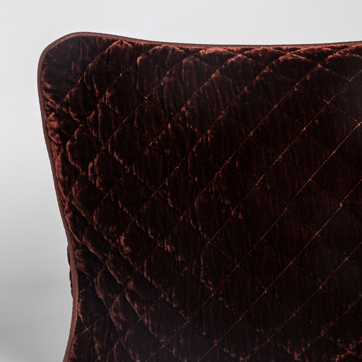 Close-up of Bella Notte Silk Velvet Quilted Throw Pillow corner in Autumn, showing diamond quilt pattern.