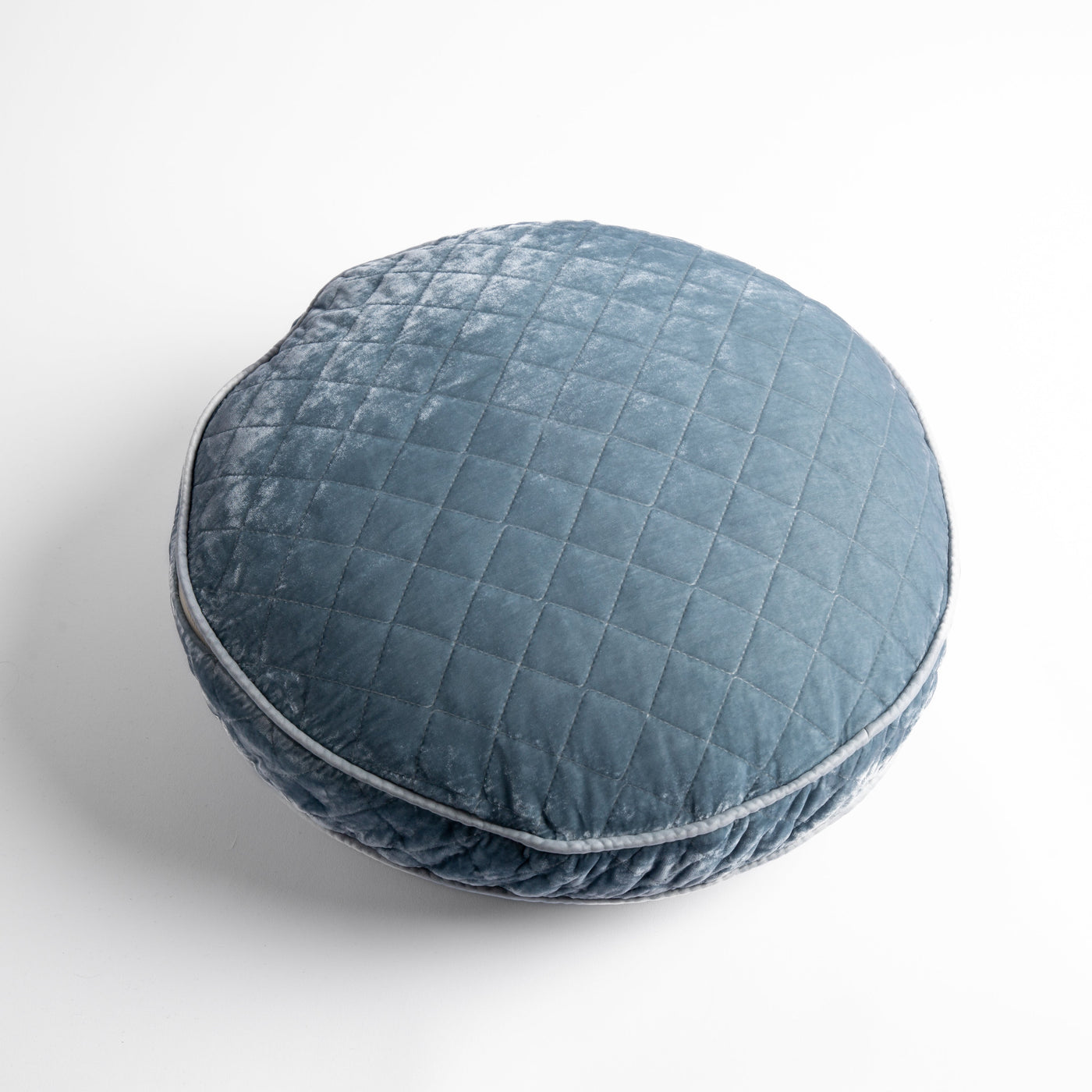 Round Bella Notte Silk Velvet quilted pillow in Cloud, with diamond stitching and piped edge.